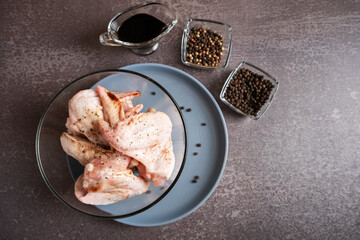 Chicken wings drizzled with soy sauce in a transparent plate for baking in teriyaki sauce. A dish of Asian cuisine.