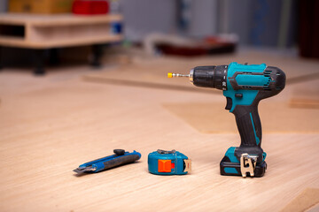 Electric cordless drill driver on the background of a carpentry shop, a professional tool for home repair, a hand power tool, copy space.