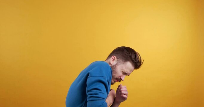 Scared young man dodging something on yellow background