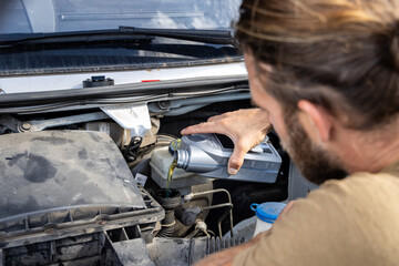 Man refilling oil into the engine of a van