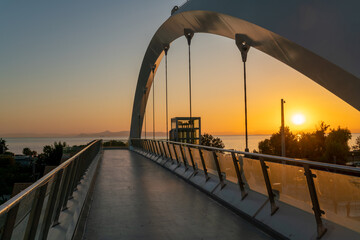 Pedestrian bridge over a busy road in the city at sunset