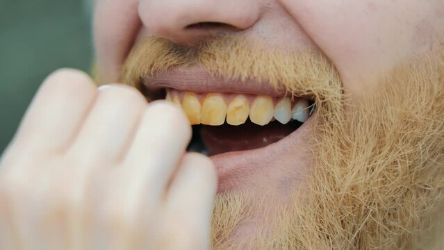 A woman paints her teeth with yellow paint. The stylist makes up the actor. Yellow teeth in a man.
