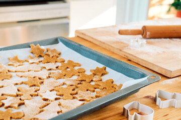 Baking sheet with christmas gingerbread cookies a shape of gingerbread man, christmas tree and star in the kitchen. Baking homemade pastries. Christmas and New Year traditions festive food.
