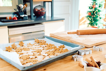 Baking sheet with christmas gingerbread cookies a shape of gingerbread man, christmas tree and star in the kitchen. Baking homemade pastries. Christmas and New Year traditions festive food.