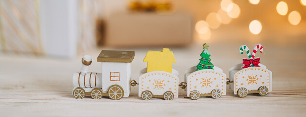 Close up of train toy decoration with with Christmas tree garland lights flickering in background. shallow depth of field. xmas gift card concept.