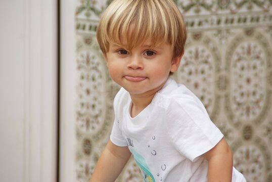 Portrait of a blonde toddler sticking out his tongue