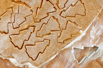 Flatted dough for christmas gingerbread cookies with cutted biscuits a shape of christmas tree. Baking homemade pastries from online recipe. Christmas and New Year traditions festive food.