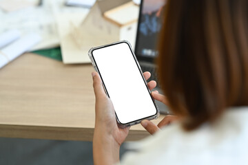 Over shoulder view of Architects woman using mobile phone while sitting at her workplace