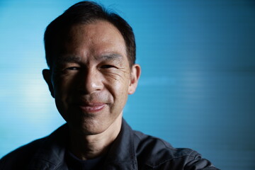 A craftsman poses in gray work clothes in front of blue shutter of a factory. Conceptual images of the essence of manufacturing, technical succession and the challenge of high-precision machining.
