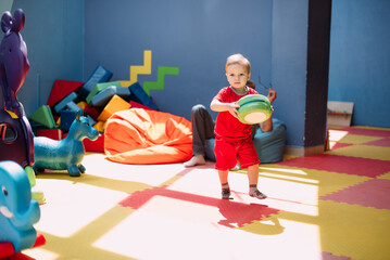 Happy laughing boy 1-2 years old having fun in ball pit  in kids amusement park and indoor play...