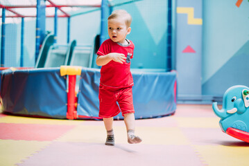 Happy laughing boy 1-2 years old having fun in ball pit  in kids amusement park and indoor play center. Activity toys for little kid