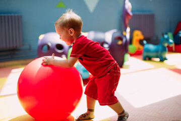 Happy laughing boy 1-2 years old having fun in ball pit  in kids amusement park and indoor play...