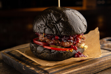 Black burger with beef, cheese and lingonberry sauce