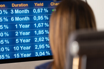 Businesswoman siting at the desk and looks the current interest rates on the Screen. Close-up...