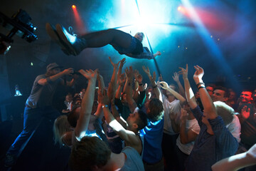 Music artist, stage dive and concert for party, nightclub or dance festival in the crowd or audience indoors. DJ, music concert and crowds of people ready to catch performer in celebration for event - Powered by Adobe