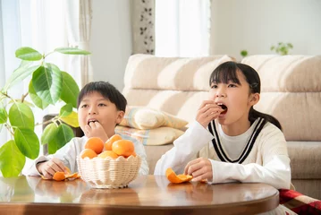 Fotobehang リビングのこたつでみかんを食べているアジア人の子供 © tatsushi