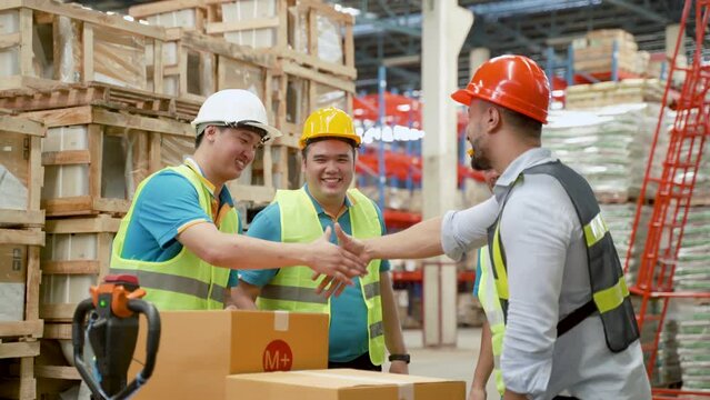 4K, The new warehouse chief clerk is congratulating and acquainted with the employees who are preparing goods in the warehouse. Four men shook hands congratulating them on meeting each other.