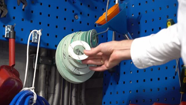 Male hand taking circular flange gasket from storage position on blue tool board