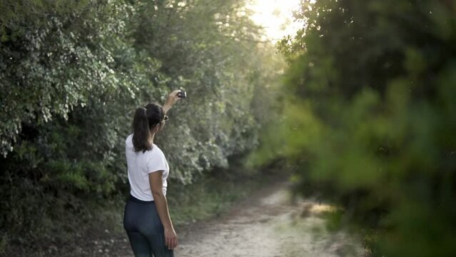 model videoing herself while walking through a hiking route in the forest