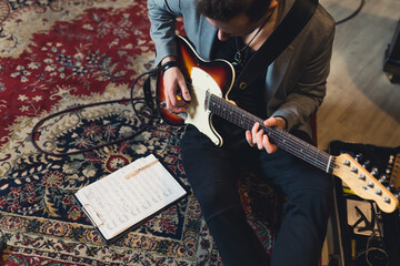 Man playing electric guitar and reading music sheet. High quality photo