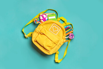 Back to school, education concept Yellow backpack with school supplies - notebook, pens, eraser rainbow, numbers isolated on blue background Top view Copy space Flat lay composition Banner