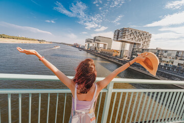 A tourist girl stands on the bridge over the Rhine River and admires the panoramic wonderful view...