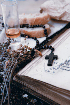 Religious (Catholic) style in fusion style (vintage, retro), the symbols of faith are depicted in bread and wine, a rosary with a cross, and an old book of the Bible