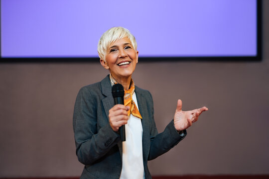 Portrait Of A Beautiful Senior Woman, Holding A Microphone, Giving A Speech.