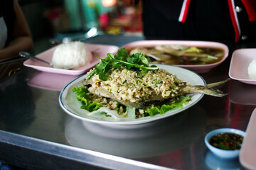 Closeup dish of deep fried fish covered by the minced garlic and coriander on the food