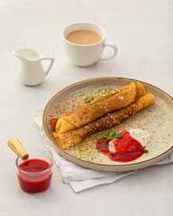 Portion of sweet crepe bliny roll with cream and jam