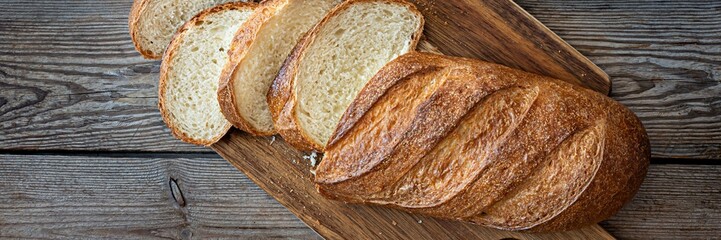 Freshly baked loaf on a wooden board on wooden background. Traditional fresh bread in the form of a...