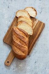 Freshly baked loaf on a wooden board on a light gray (blue) background. Traditional fresh bread in...