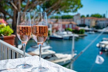 Drinking of French brut champagne sparkling wine in glasses in yacht harbour of Port Grimaud near Saint-Tropez, French Riviera vacation, France