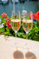 Drinking of French brut champagne sparkling wine in glasses in yacht harbour of Port Grimaud near Saint-Tropez, French Riviera vacation, France