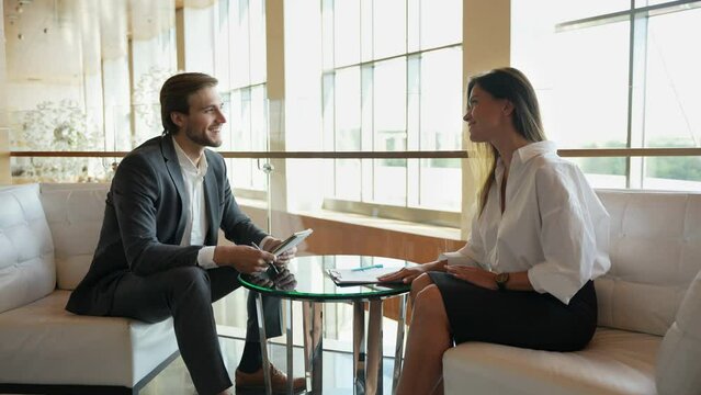 Middle-aged female manager provides information, makes presentation, talking to male company client in office. Two employees, workmates discuss new project, software or business app