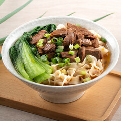 Beef noodle soup. Taiwanese famous food in a bowl on wooden table.