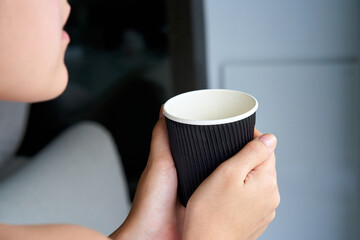 Close-up of a girl drinking coffee from a black cardboard cup