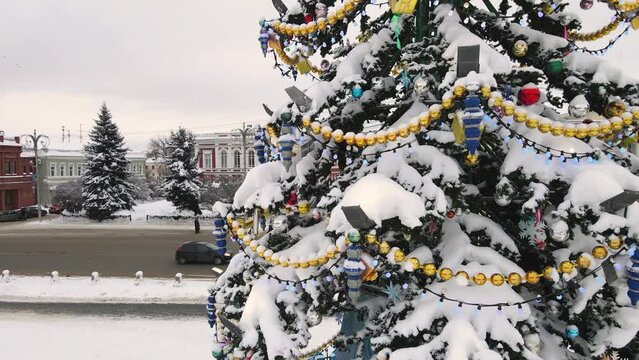 Close-up of toys and beautiful garlands on a Christmas tree, aerial view. New Year's, green spruce fabulously decorated and covered with snow. City of Vladimir, Cathedral Square, Russia. UHD 4K.