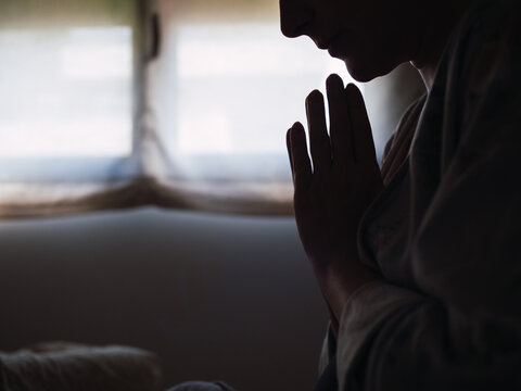 Silhouette of woman praying by the window