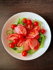 vertical photo. salad of fresh tomatoes and arugula. healthy vitamin food. vegetarian diet. ripe red tomatoes topped with slices. eco. bio.