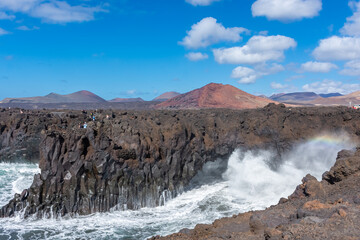 Beautiful rainbow caused by the crashing of the Ocean waves against the volcanic cliffs of Los Hervideros, Lanzarote, Canary Islands, Spain