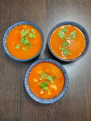 large vertical photo. thai soup tom yum. top view of three servings of soup in blue bowls with a pattern. spicy soup with shrimp. eco. bio.