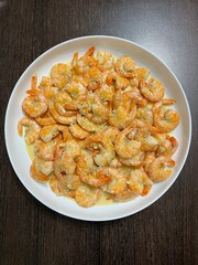 vertical photo. boiled northern shrimps on a round white plate. view from above. healthy food. balanced diet. seafood. eco.