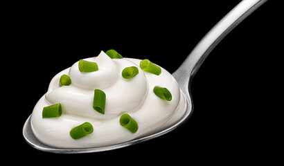 Spoon of sour cream with green onion on black background