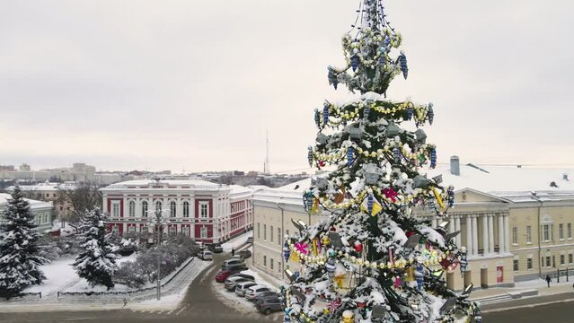 Christmas tree in the city square with toys and golden garlands, aerial view. New Year's, green spruce fabulously decorated and covered with snow. City of Vladimir, Cathedral Square, Russia. UHD 4K.