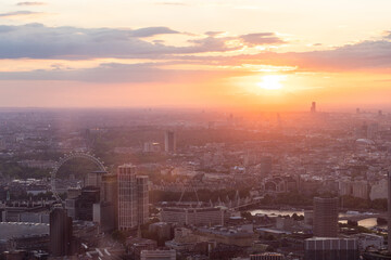 Panoramic view of London city skyline illuminated by colorful sunset light, aerial shot. Famous landmark buildings and architectural attractions on the river banks.