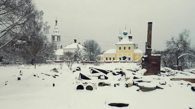 Aerial view of a destroyed stove in winter with a tall charred chimney. War, a bombed-out house, a consequence of the bombing, rocket attacks. Snow-covered ruins abandoned by people. UHD 4K.