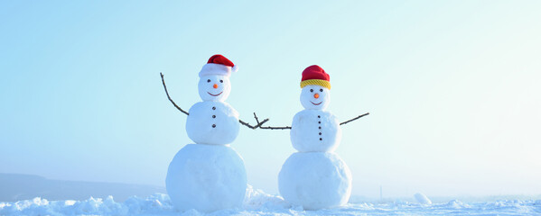 Funny couple of two snowman holding hands outdoors. Snowman on the snow outdoor background....