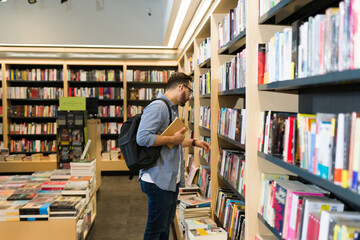 Caucasian man with a backpack browsing the bookshelves at the store