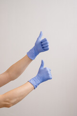 Close up of Doctors or cosmetologist hands in protective gloves showing thumbs up on white background